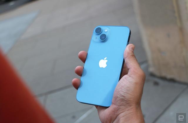 The iPhone 14 held in a hand with its rear cameras facing out.
