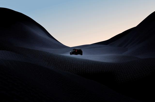 A teaser photo for the Volvo EX30 small SUV showing the silhouette of a small vehicle driving across a dark hilly terrain.