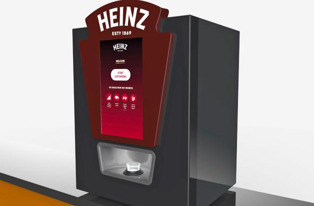 A computer rendering of the Heinz Remix sauce dispenser, showing a rectangular device with the Heinz logo at the top, four buttons on the front and a dispenser trough just below that.