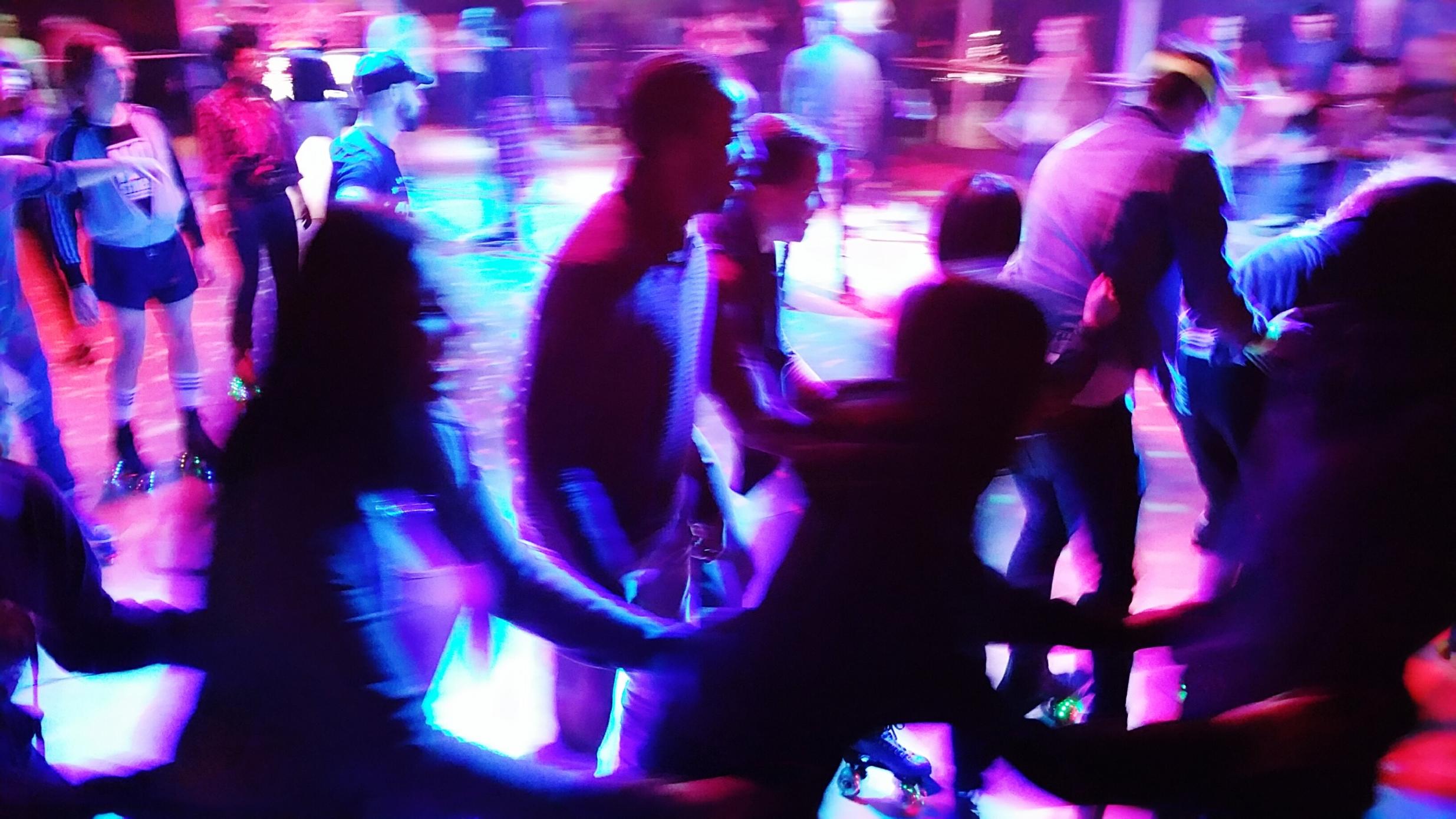 Blurred Motion Of People Enjoying At Roller Disco At Night