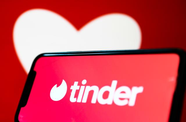 Tinder logo displayed on a phone screen and a heart shape displayed on a screen in the background are seen in this illustration photo taken in Krakow, Poland on February 13, 2022. (Photo by Jakub Porzycki/NurPhoto via Getty Images)