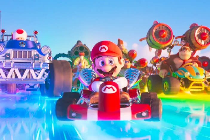 Mario races down a track with Toad and Donkey Kong behind him. 